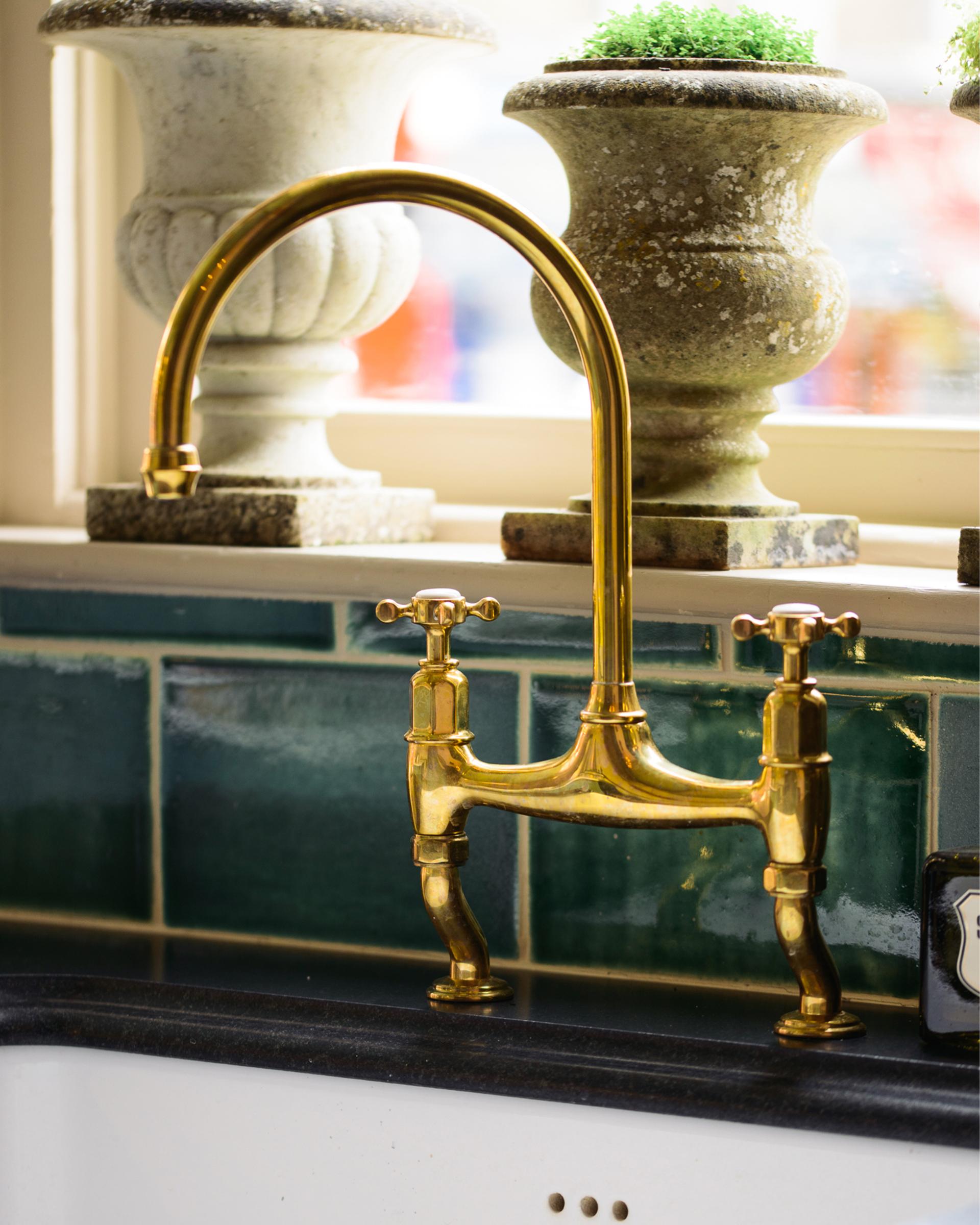 A close-up oblique view of a traditional-style aged brass mixer tap with crosshead handles.