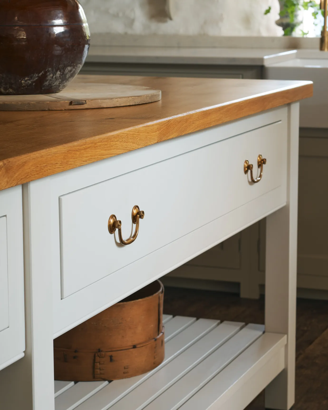 An angled view of an elegant Georgian-style brass swing handle fitted to a light painted kitchen drawer.