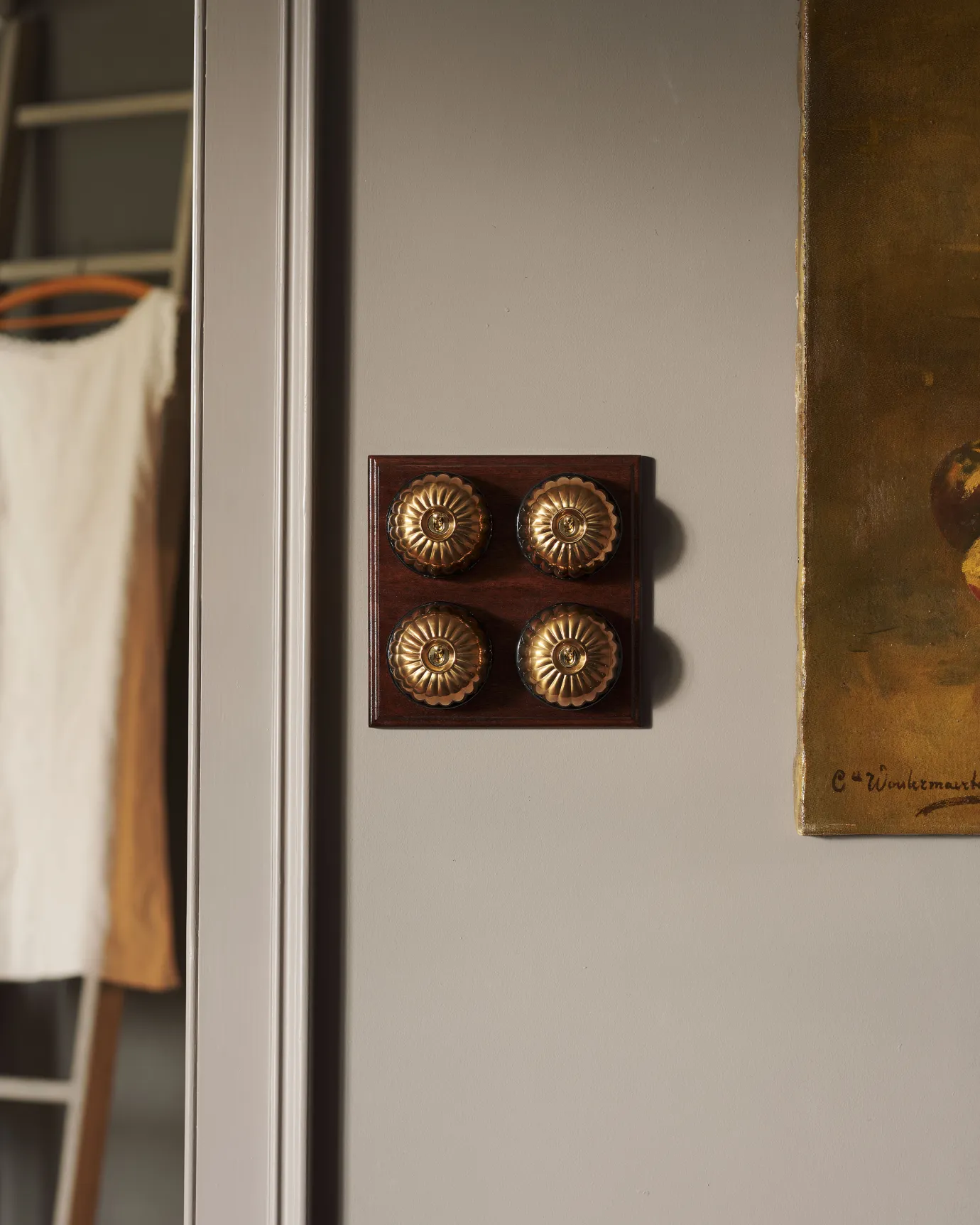 A 4 gang bank of Jelly toggle light switches in an Heirloom Brass finish, with black ceramic bases and a Stained Sapele pattress.
