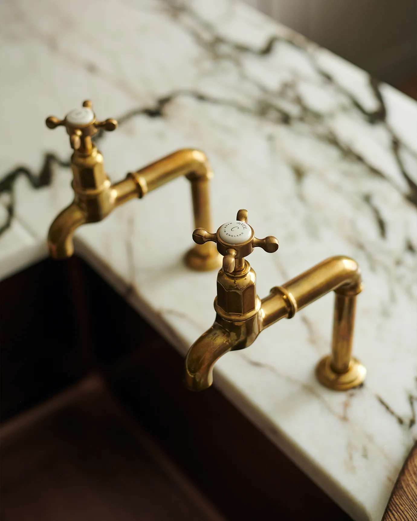 A pair of traditional-style aged brass bibcock taps with crosshead handles.