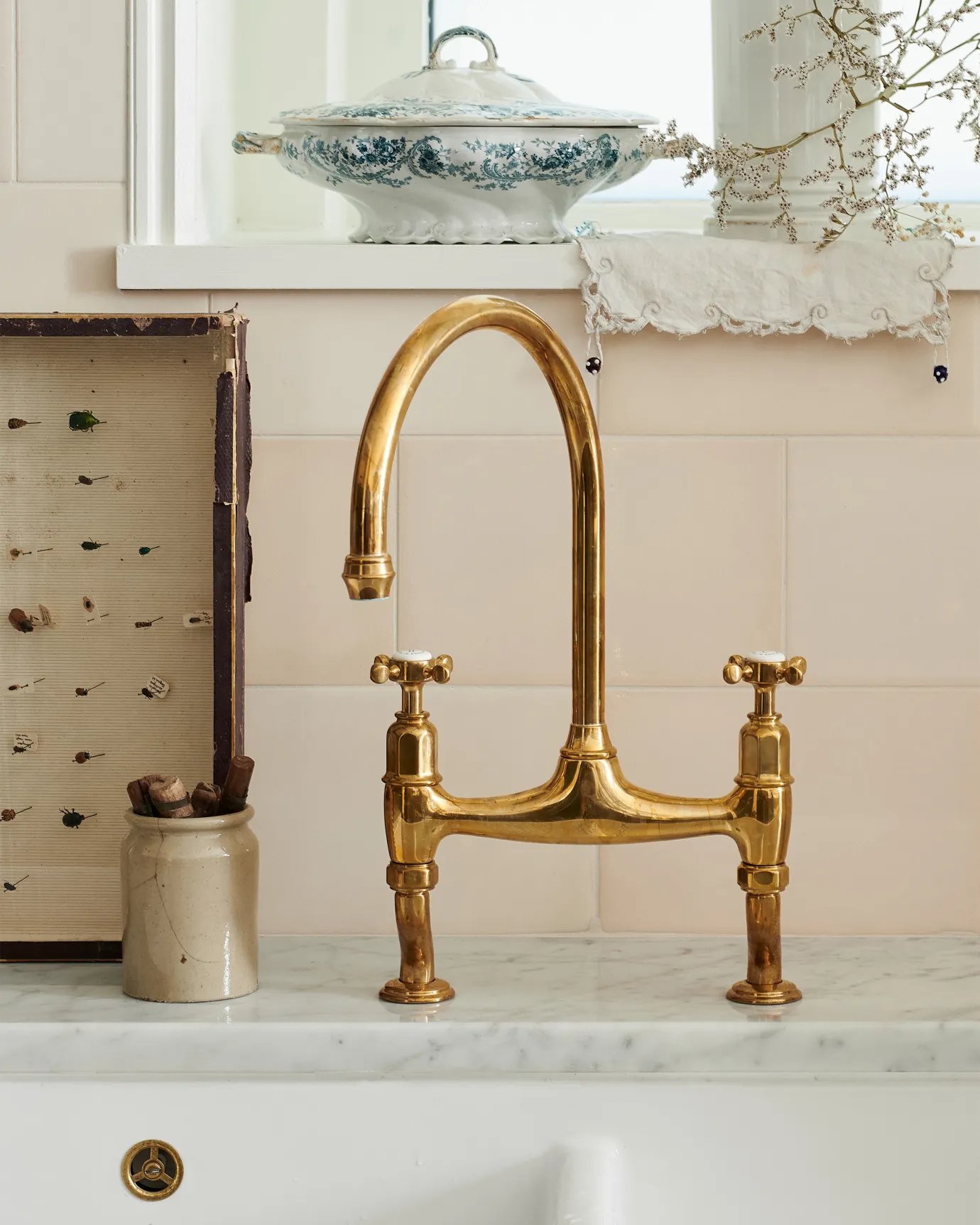 A straight-on view of a traditional-style aged brass mixer tap with crosshead handles.