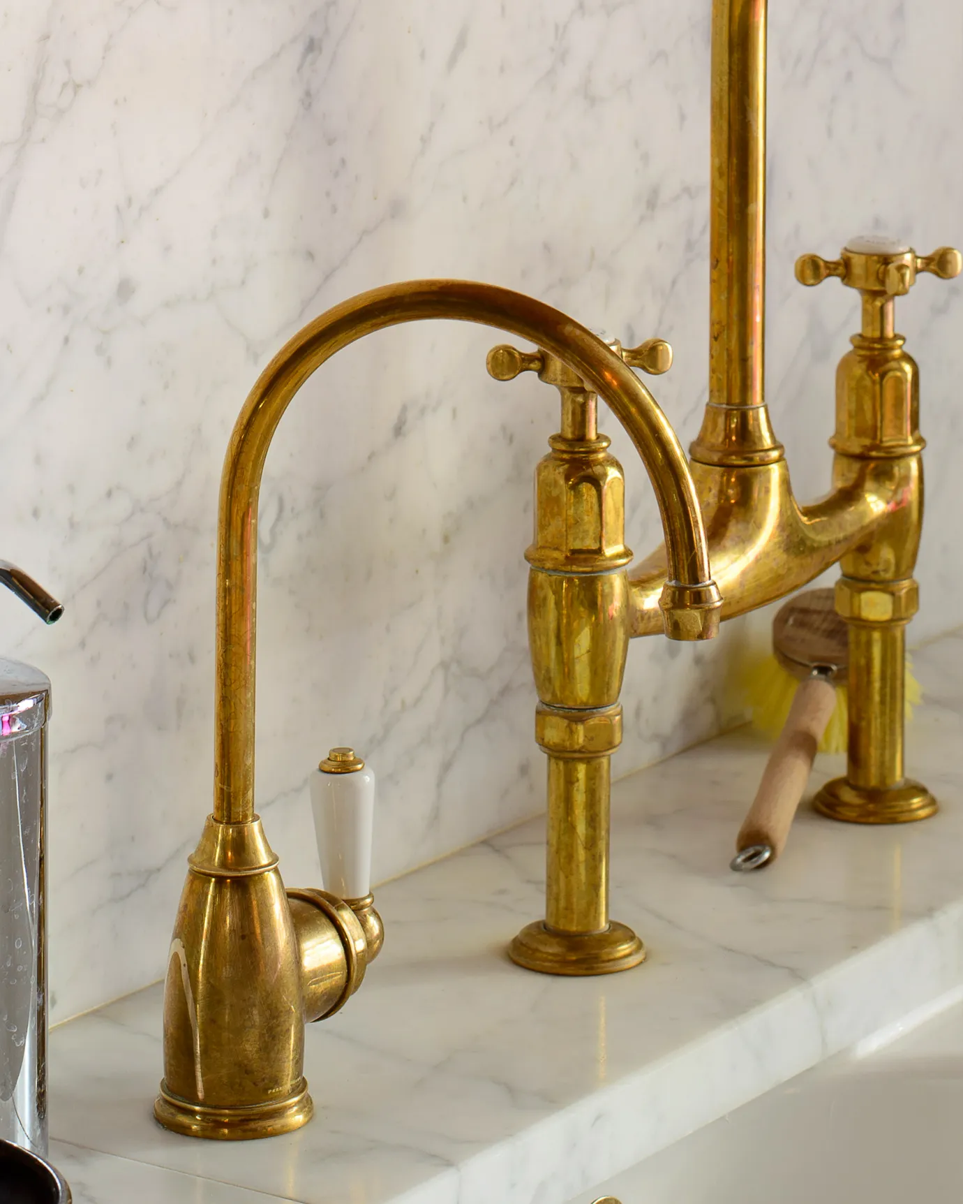 A close-up view of a small traditional-style aged brass tap with a white ceramic lever.