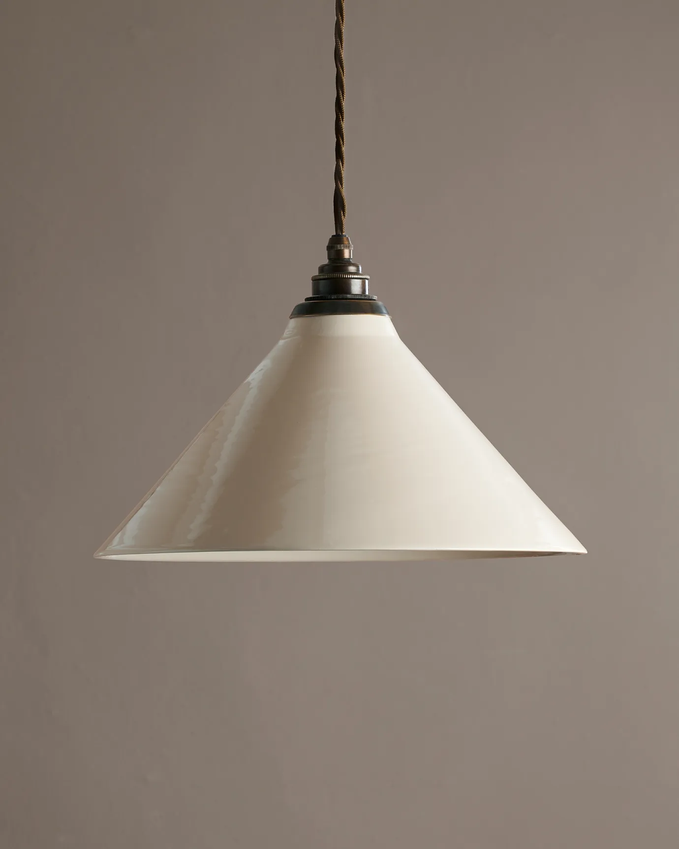 A large cream glazed ceramic pendant light with an aged brass E27 lampholder and cuff and brown twisted fabric flex cord.