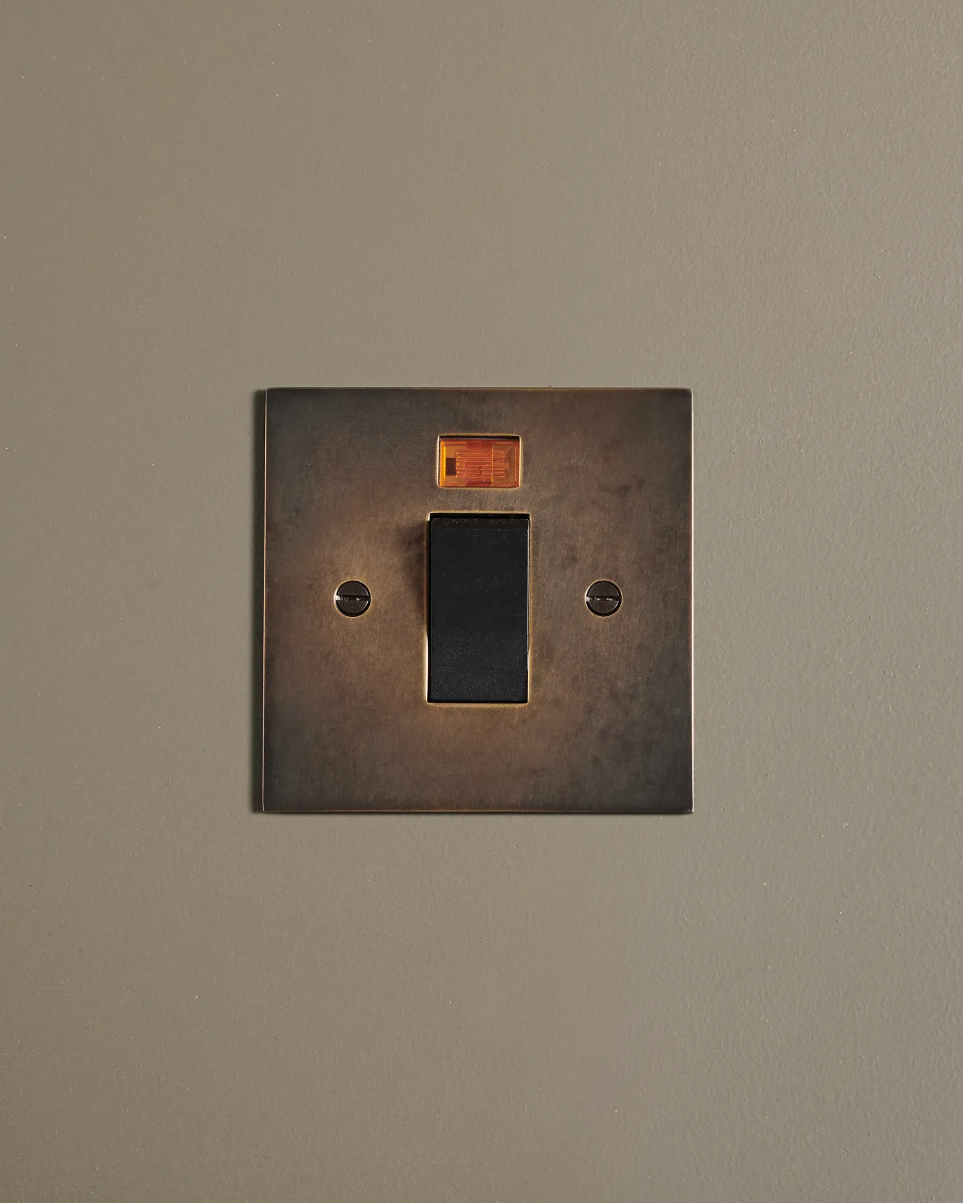 A straight-on view of a classic 45 amp cooker switch in a dark oxidised brass finish.