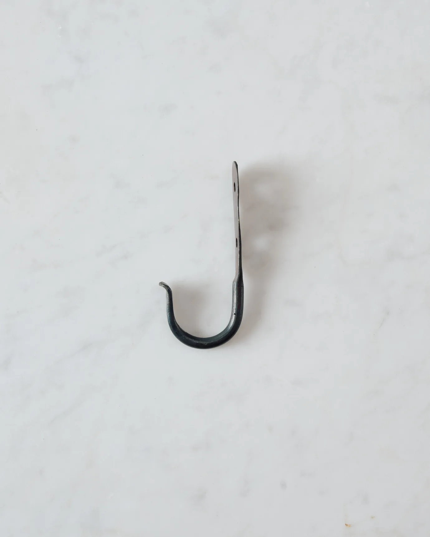 A side profile view of a small iron wall hook.
